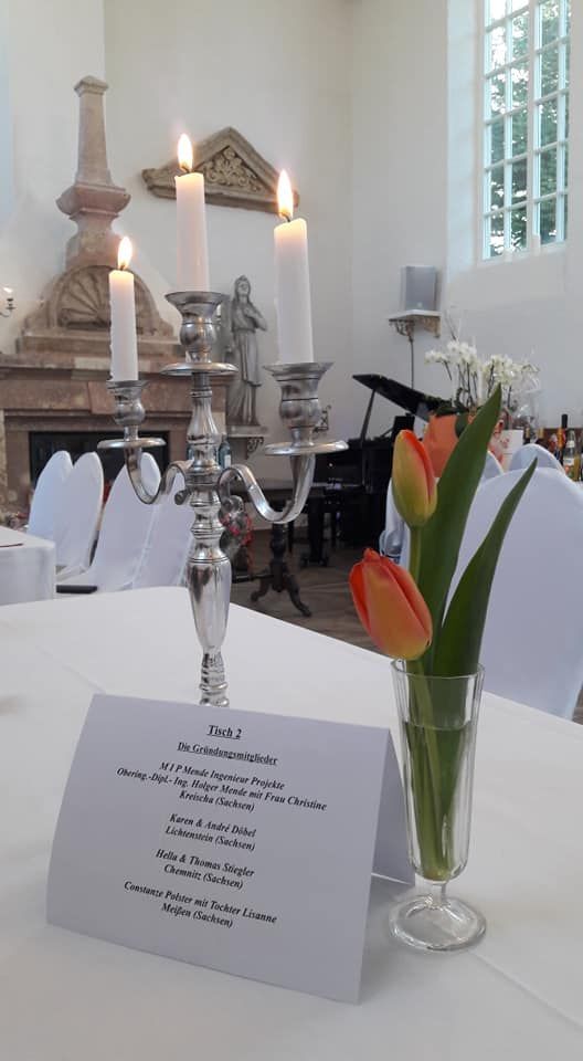 Eingedeckter Tisch mit Kerzenleuchter und Tulpen in der Kapelle