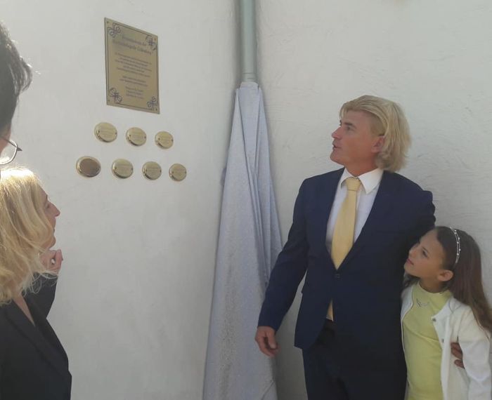 Gäste vor der Ehrentafel an der Wand der Kapelle