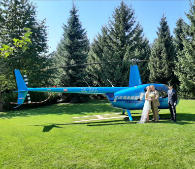 Brautpaar vor einem Hubschrauber auf dem Helikopter-Landeplatz im Park